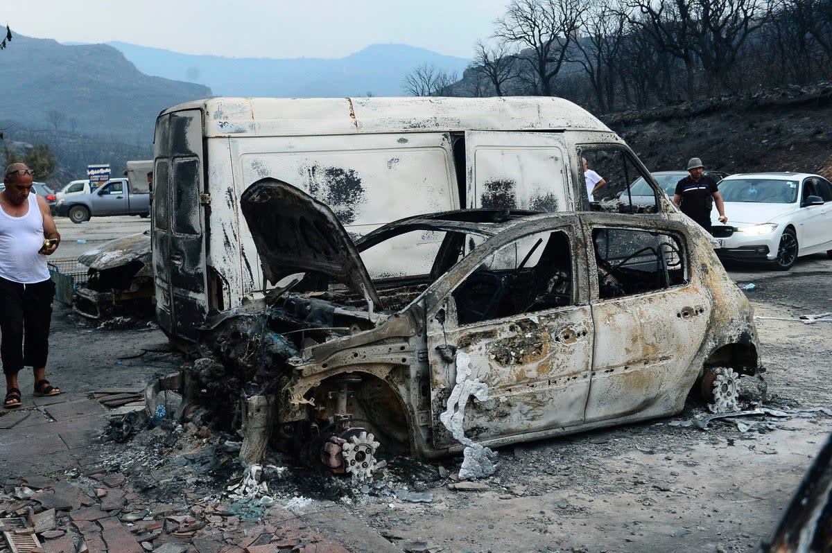 People inspect burnt vehicles after wildfire devastates Bouira, 100 km from Algiers (AP)