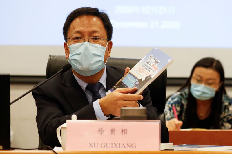 Xu Guixiang, deputy head of Xinjiang's publicity department holds a copy of a booklet, as he speaks during a news conference in Beijing