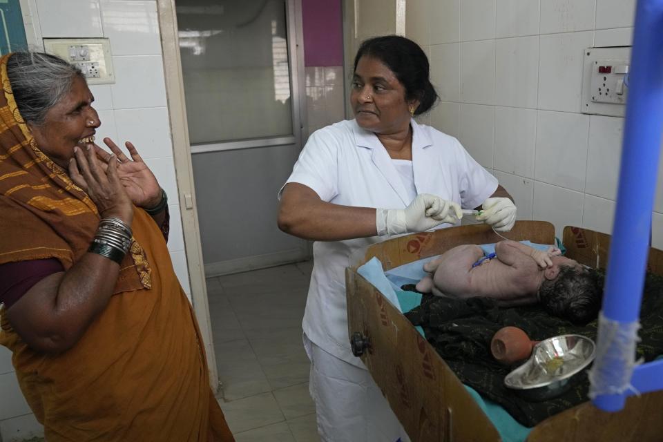 An elderly woman reacts after seeing a newly born baby of her relative at a government maternity hospital which runs on rooftop solar power, in Raichur, India, Wednesday, April 19, 2023. Government Maternity installed rooftop solar panels about a year ago and can now depend on constant electricity that keeps the lights on, patients and staff comfortable and vaccines and medicines safely refrigerated. (AP Photo/Aijaz Rahi)