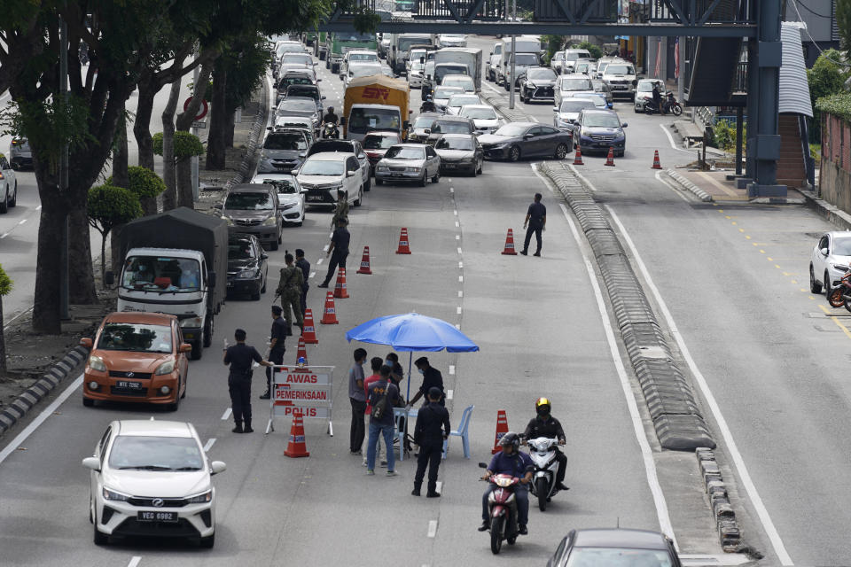 Police officers check vehicles at a roadblock to ensure that people abide by a movement control order in downtown Kuala Lumpur, Malaysia, Wednesday, Oct. 14, 2020. Malaysia will restrict movements in its biggest city Kuala Lumpur, neighboring Selangor state and the administrative capital of Putrajaya from Wednesday to curb a sharp rise in coronavirus cases. (AP Photo/Vincent Thian)