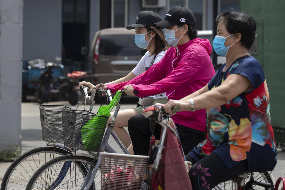 Residents wearing masks to curb the spread of the coronavirus ride past a neighborhood under lockdown in Beijing Tuesday, June 16, 2020. Chinese authorities locked down a third neighborhood in Beijing on Tuesday as they rushed to prevent the spread of a new coronavirus outbreak that has infected more than 100 people in a country that appeared to have largely contained the virus. (AP Photo/Ng Han Guan)