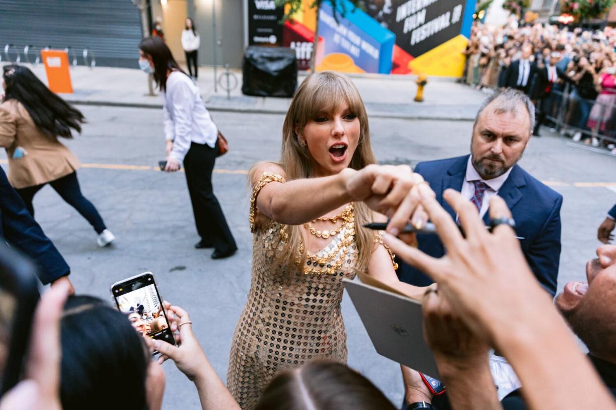 A celebrity signs autographs and greets fans.