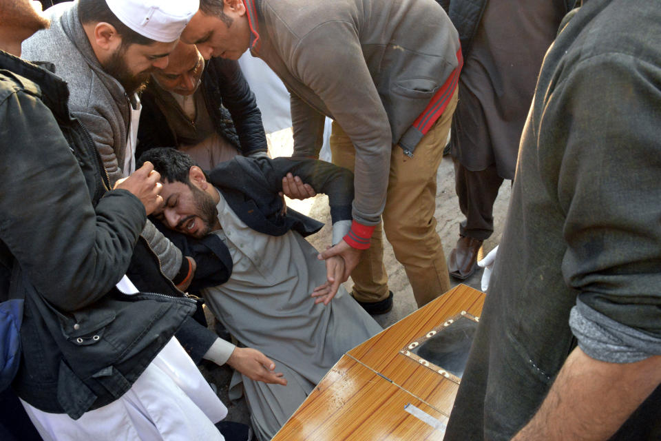 People comfort a man mourning next to coffin of his family member, who was killed in the suicide bombing inside a mosque, at a hospital, in Peshawar, Pakistan, Monday, Jan. 30, 2023. A suicide bomber struck Monday inside a mosque in the northwestern Pakistani city of Peshawar, killing multiple people and wounding scores of worshippers, officials said. (AP Photo/Muhammad Riaz)