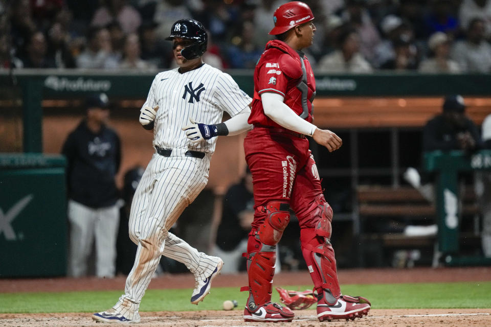 New York Yankees' Carlos Narvaez, left, scores past Diablos Rojos' catcher Jose Briceno during an exhibition baseball game at Alfredo Harp Helu Stadium in Mexico City, Monday, March 25, 2024. (AP Photo/Fernando Llano)