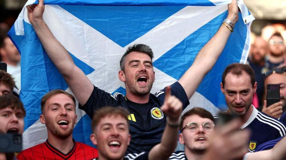 A Scotland fan holding a Saltire cheers 