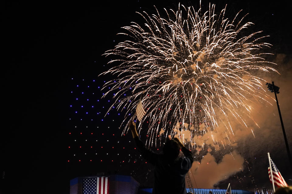 A supporter of President-elect Joe Biden waves and American flag as fireworks go off Saturday, Nov. 7, 2020, in Wilmington, Del. (AP Photo/Andrew Harnik)