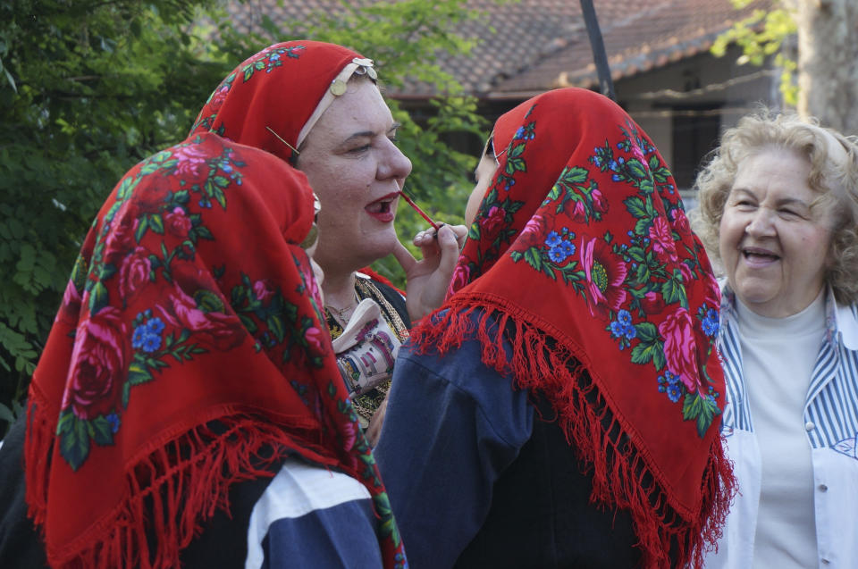 Dancers dressed in traditional Thrace dresses put on the finishing touches of make-up before performing around a fire set up in a residential street for a firewalking ritual in Lagkadas, Greece, on Monday, May 22, 2023. Groups of devotees of St. Constantine called "anastenaria" celebrate his feast day with elaborate rituals that include carrying icons barefoot over a bed of burning coals. (AP Photo/Giovanna Dell'Orto)