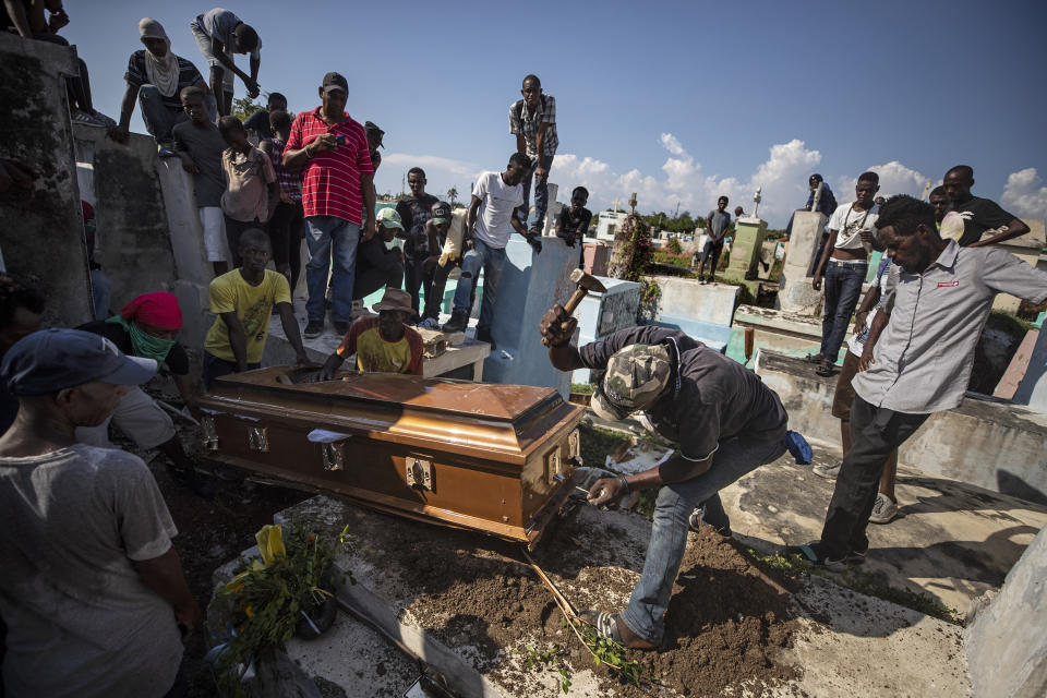 A man uses a hammer to remove pieces of a coffin to make it fit inside the grave during the burial of a person killed during a month of demonstrations aimed at ousting Haitian President Jovenel Moise, at a cemetery in central Port-au-Prince, Haiti, Oct. 16, 2019. The image was part of a series of photographs by Associated Press photographers which was named a finalist for the 2020 Pulitzer Prize for Breaking News Photography. (AP Photo/Rebecca Blackwell)