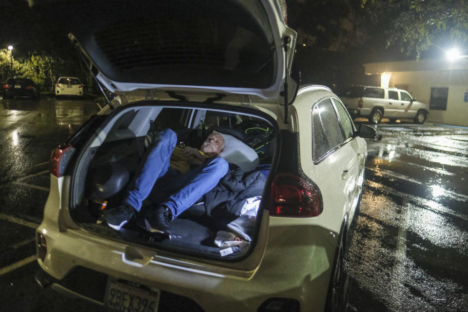 Duck Derrington, 61 of Lompoc, sleeps in his car at the parking lot of an evacuation center in Santa Barbara, Calif., Monday, Jan. 9, 2023. (AP Photo/Ringo H.W. Chiu)