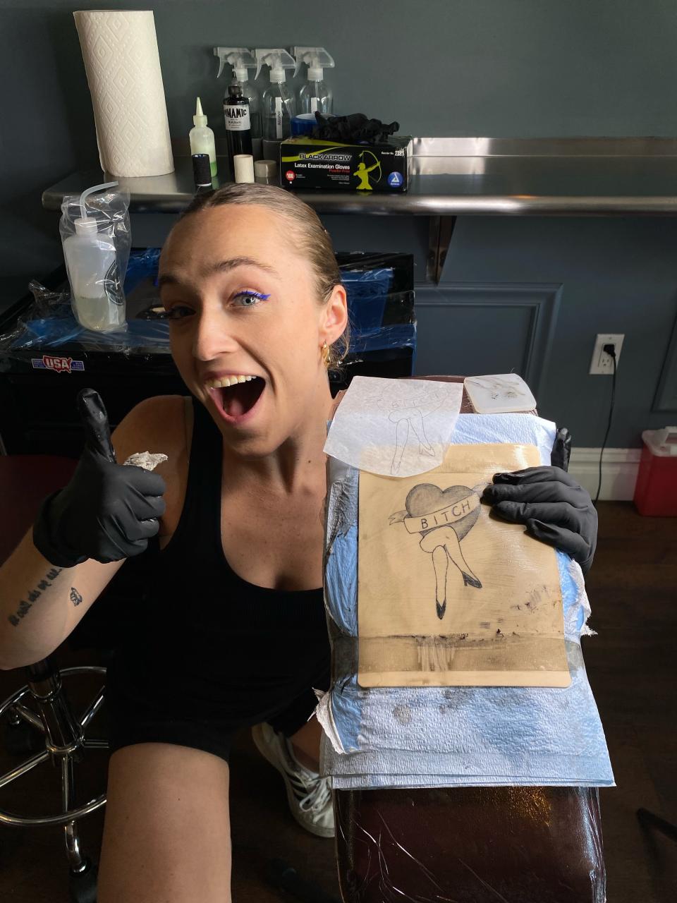 Syd Robinson holding up her tattoo