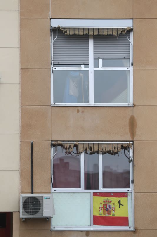 FOTO DE ARCHIVO: Una bandera española y una cinta negra de luto se exhiben en un edificio mientras una anciana es vista a través de su ventana durante el brote de la enfermedad coronavirus (COVID-19) en Madrid, España