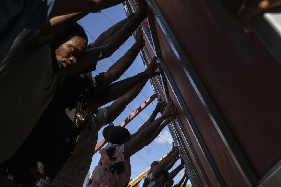 FILE - Neighbors raise a metal gate as they work to install it as a barricade against gangs, in the Petion-Ville neighborhood of Port-au-Prince, Haiti, Saturday, April 20, 2024. Haiti's health system has long been fragile, but it's now nearing total collapse after gangs launched coordinated attacks on Feb. 29, targeting critical state infrastructure in the capital and beyond. (AP Photo/Ramon Espinosa)