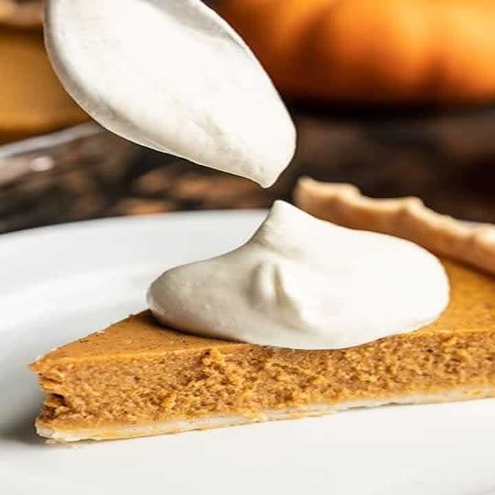 Pumpkin pie being dolloped with whipped cream