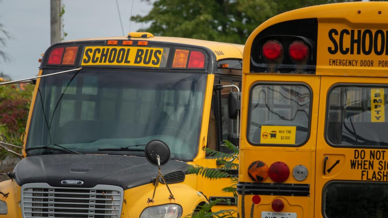 Two school buses parked at a depot in Ottawa in September 2021. The authority that manages school bus transportation for the Ottawa-Carleton District School Board and Ottawa Catholic School Board says it can't use savings from cancelled routes to compensate parents. (Francis Ferland/CBC - image credit)