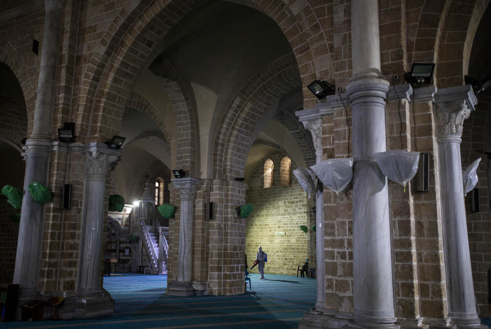 Palestinian Health workers spray disinfectant as a precaution against the coronavirus in the Al-omari mosque in Gaza City, Thursday, March 12, 2020. (AP Photo/Khalil Hamra)