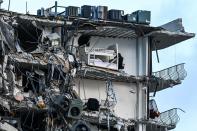 <p>Rubble and debris hang from the collapsed structure of the beachfront high-rise.</p>