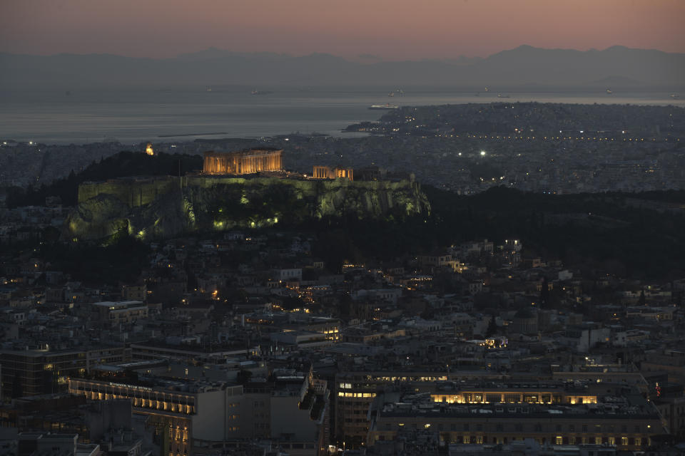 The 5th Century B.C. Parthenon temple is lighted atop the ancient Acropolis hill as in the back ground ferries sale in the Saronic golf, in Athens, on Wednesday, April 10, 2019. (AP Photo/Petros Giannakouris)