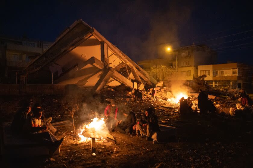 ©2023 Tom Nicholson. 10/02/2023. Adiyaman, Turkey. Internally displaced people sit around camp fires surrounded by destroyed buildings in Adiyaman, Turkey, following the earthquake on 6 February. Over 23,000 people across Syria and Turkey have died, whilst vast surrounding areas are also suffering severe damage to infrastructure.