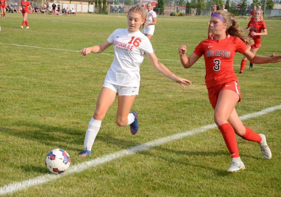 Milan's Emma Budd and Olivia Zuccaro of Grosse Ile race for a loose ball at the edge of the goal box in the finals of the Division 3 District at Milan Friday night.  Grosse Ile won 2-1 on a penalty-kick shootout.