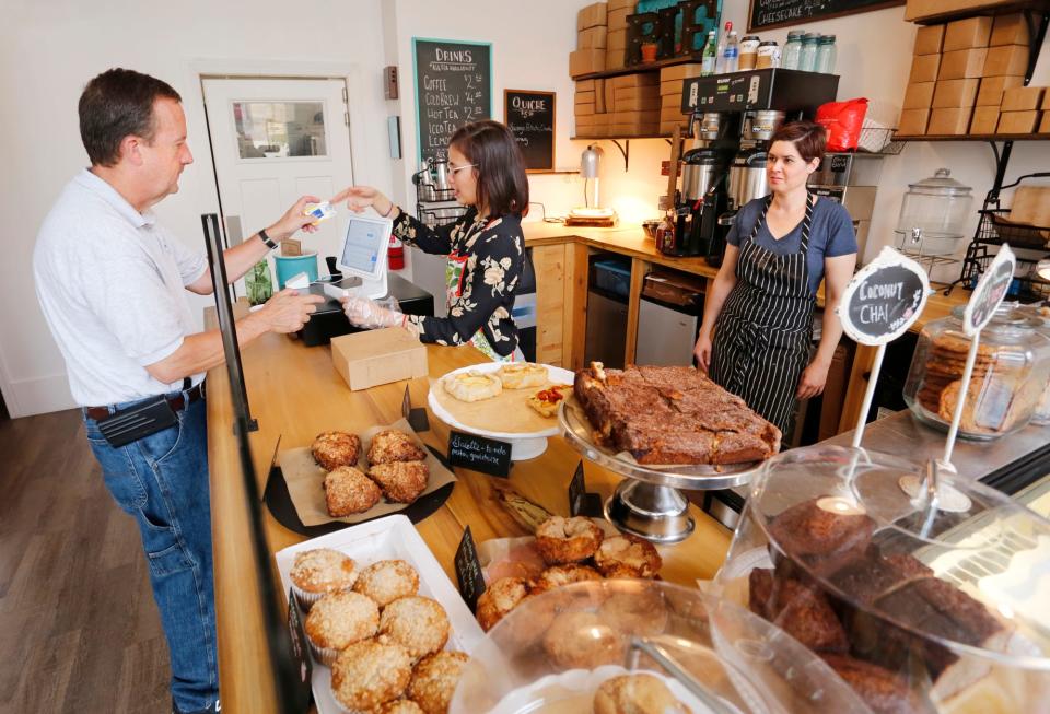 In this file photo, owner Sarah Ray, right, looks on as Callum Amigleo rings up the purchase of Bruce Stewart Friday, October 6, 2017, at Sweet Revolution Bake Shop, 109 N. 5th Street in downtown Lafayette.