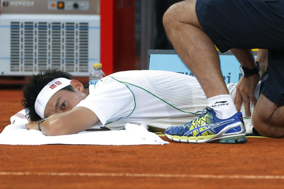 Kei Nishikori from Japan gets help from a physiotherapist during his Madrid Open tennis tournament final match against Rafael Nadal from Spain in Madrid, Spain, Sunday, May 11, 2014. (AP Photo/Andres Kudacki)