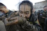 A female student opens her cufflinks with her teeth, after crawling through mud at Tianjiao Special Guard/Security Consultant camp on the outskirts of Beijing December 12, 2013. Former Chinese soldier Chen Yongqing has big ambitions for his bodyguard training school Tianjiao, which he says is China's first professional academy to train former soldiers and others as personal security guards. Chen charges 500,000 yuan ($82,400) a year for each protector as China's rich and famous look to bolster their safety and sense of importance. Picture taken December 12, 2013. REUTERS/Jason Lee (CHINA - Tags: BUSINESS SOCIETY) ATTENTION EDITORS: PICTURE 18 OF 26 FOR PACKAGE 'CHINA'S BODYGUARD SCHOOL' TO FIND ALL IMAGES SEARCH 'TIANJIAO'