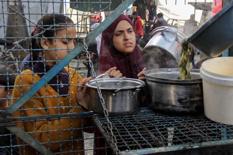 Palestinos esperan para recibir una comida gratuita compuesta de Khobiza, una verdura de hoja silvestre, durante el mes sagrado del Ramadán, en medio del actual conflicto entre Israel y Hamás, en Jabalia, en el norte de la Franja de Gaza