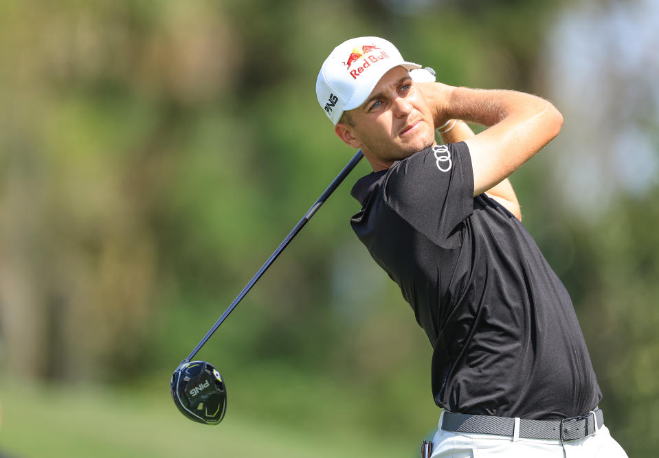 Schwab hits a tee shot in a black shirt