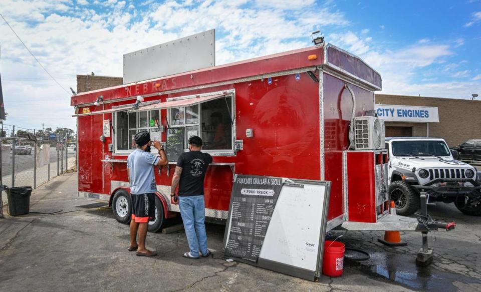 Customers Ramneek Singh, left, and Prince Singh give their orders at the Punjabi Chulla & Grill food truck on Shaw Avenue near Highway 99 in Fresno on Wednesday, Aug. 16, 2023.