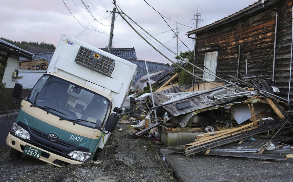 A truck is stuck on a destroyed road in Wajima, Ishikawa prefecture, Japan Friday, Jan. 5, 2024. Monday’s temblor decimated houses, twisted and scarred roads and scattered boats like toys in the waters, and prompted tsunami warnings. (Kyodo News via AP)