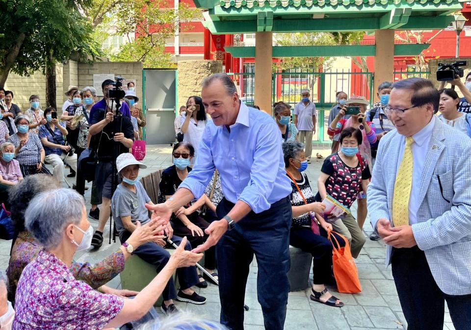 A man greets people as cameras surround them