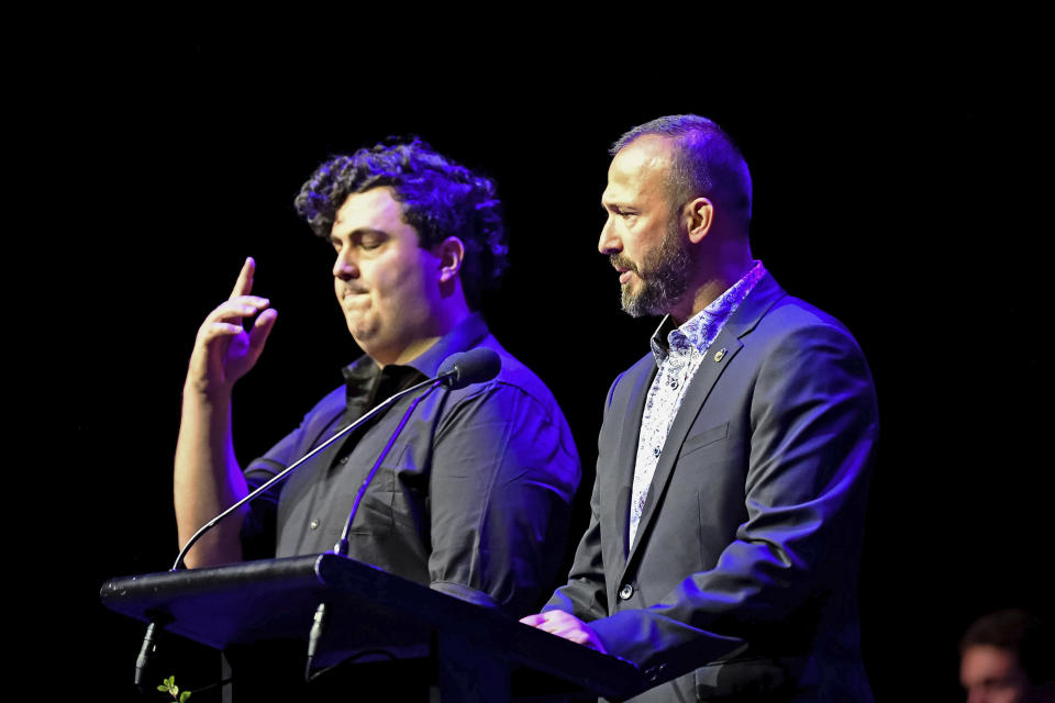 In this photo provided by the Department of Internal Affairs, Temel Atacocugu, right, who survived being shot nine times during the March 15, 2019, attack on the Al Noor mosque, speaks at a National Remembrance Service, Saturday, March 13, 2021, in Christchurch, New Zealand. Atacocugu said the slaughter was caused by racism and ignorance. The service marks the second anniversary of a shooting massacre in which 51 worshippers were killed at two Christchurch mosques by a white supremacist. (Mark Tantrum/Department of Internal Affairs via AP)