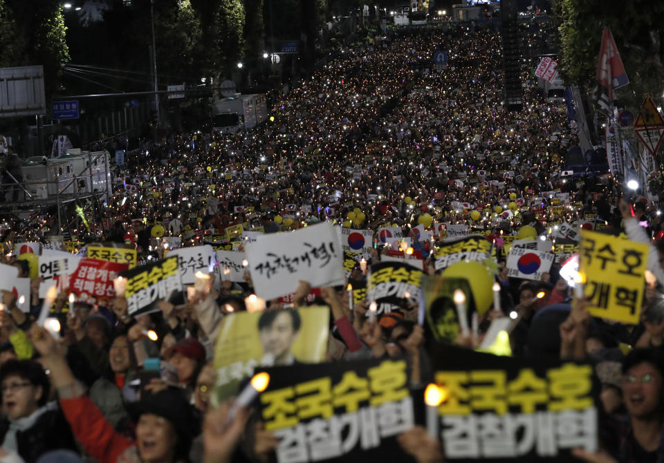 FILE- In this Oct. 12, 2019 file photo, pro-government supporters hold candles during a rally supporting Justice Minister Cho Kuk in front of Seoul Central District Prosecutors' Office in Seoul, South Korea. Cho on Monday, Oct. 14, offered to step down amid an investigation into allegations of financial crimes and academic favors surrounding his family, a scandal that has rocked Seoul's liberal government and deeply polarized national opinion. The letters read "Reform the Prosecution," and "Protect Cho Kuk." (AP Photo/Lee Jin-man, File)