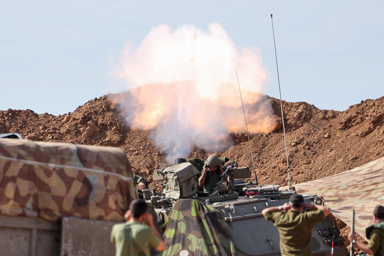 Israeli soldiers duck as they fire into Gaza from a position outside kibbutz Beeri near the border with the Palestinian strip on October 17, 2023, in the aftermath of an October 7 attack by Palestinian militants. US President Joe Biden will visit Israel on October 18 in a show of 