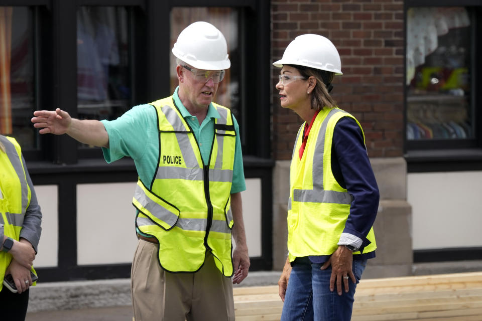 Iowa Gov. Kim Reynolds, center, talks with Davenport Mayor Mike Matson, left, while touring the site of an apartment building collapse, Monday, June 5, 2023, in Davenport, Iowa. The six-story, 80-unit building partially collapsed May 28. (AP Photo/Charlie Neibergall)