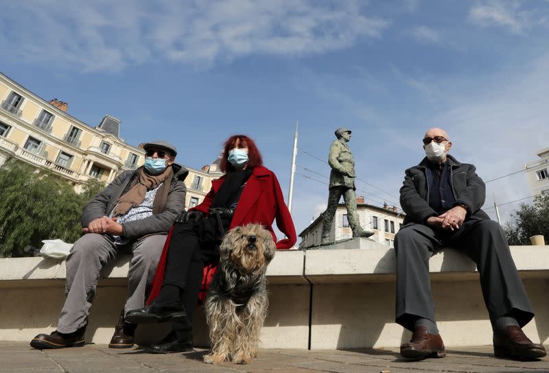 People wearing protective face masks sit in a local market in Nice