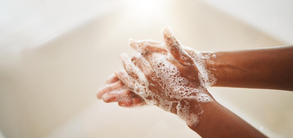 Hands lathered with soap under running water, demonstrating proper handwashing technique