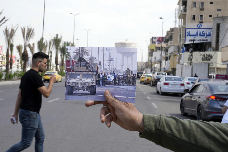 A photograph of a army vehicle securing the area where a suicide car bomber targeted a government convoy, in Bab al-Sharji area, central Baghdad, Thursday, Oct. 23, 2008, is inserted into the scene at the same location on Tuesday, March 21, 2023, 20 years after the U.S. led invasion on Iraq and subsequent war. (AP Photo/Hadi Mizban)