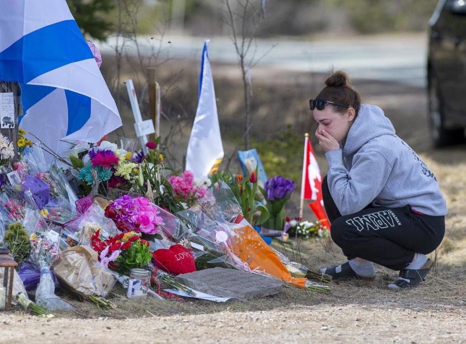 A woman pays her respects to the victims of the mass shooting at a roadside memorial on Portapique Road in Portapique, Nova Scotia