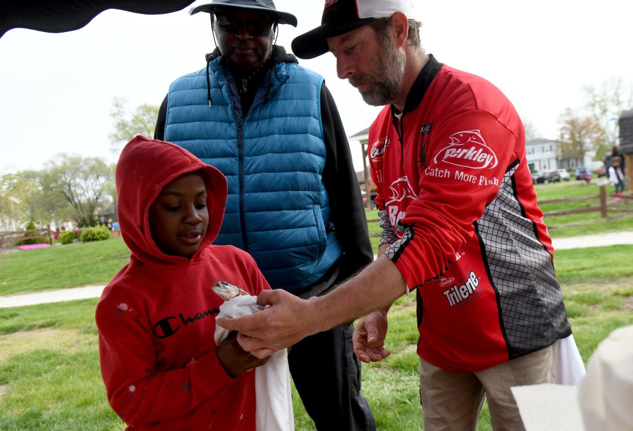 Jeremy Ducksworth, 6, of Canton with uncle, Mark Dunivant, weighs his catch with the help of Shane Schafternocker of Louisville during The Jack Cullen Towpath Trail Trout Derby at St. Helena Heritage Park in Canal Fulton.