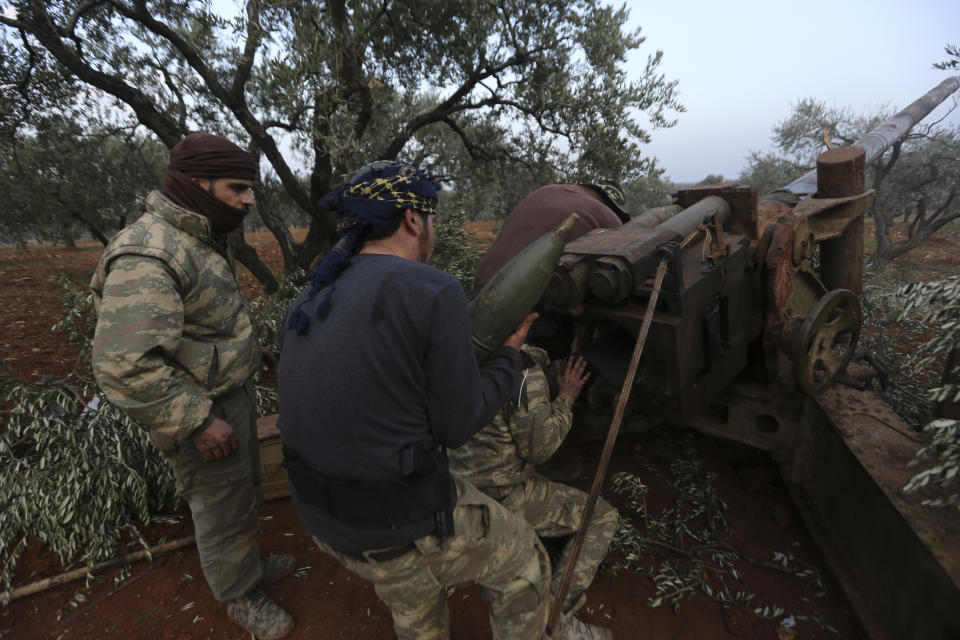 Syrian rebel fighters prepare to shoot a howitzer toward the government positions near the village of Nerab, in Idlib province, Thursday, Feb. 6, 2020. Turkey sent more reinforcements into northwestern Syria on Thursday, setting up new positions in an attempt to stop a Syrian government offensive on the last rebel stronghold in the war-torn country, state media and opposition activists said. (AP Photo/Ghaith Alsayed)