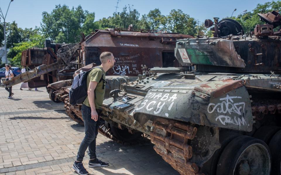 Image shows tourist inspecting burnt-out tank on display in Kiev