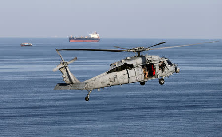 FILE PHOTO: A MH-60S helicopter hovers in the air with an oil tanker in the background as the USS John C. Stennis makes its way to the Gulf through the Strait of Hormuz, December 21, 2018. REUTERS/Hamad I Mohammed/File Photo