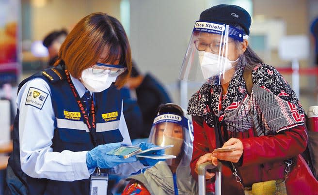 在桃園機場入境管制區內，1名防疫人員正在查驗旅客的健康聲明書。（范揚光攝）