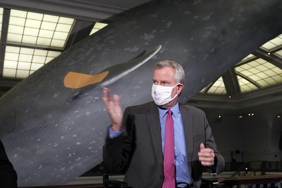 New York Mayor Bill de Blasio gestures as he sits in front of the 94-foot-long, 21,000-pound model of a blue whale, wearing a bandage, at COVID-19 vaccination site in the Milstein Family Hall of Ocean Life, at the American Museum of Natural History, in New York, Friday, April 23, 2021. (AP Photo/Richard Drew)