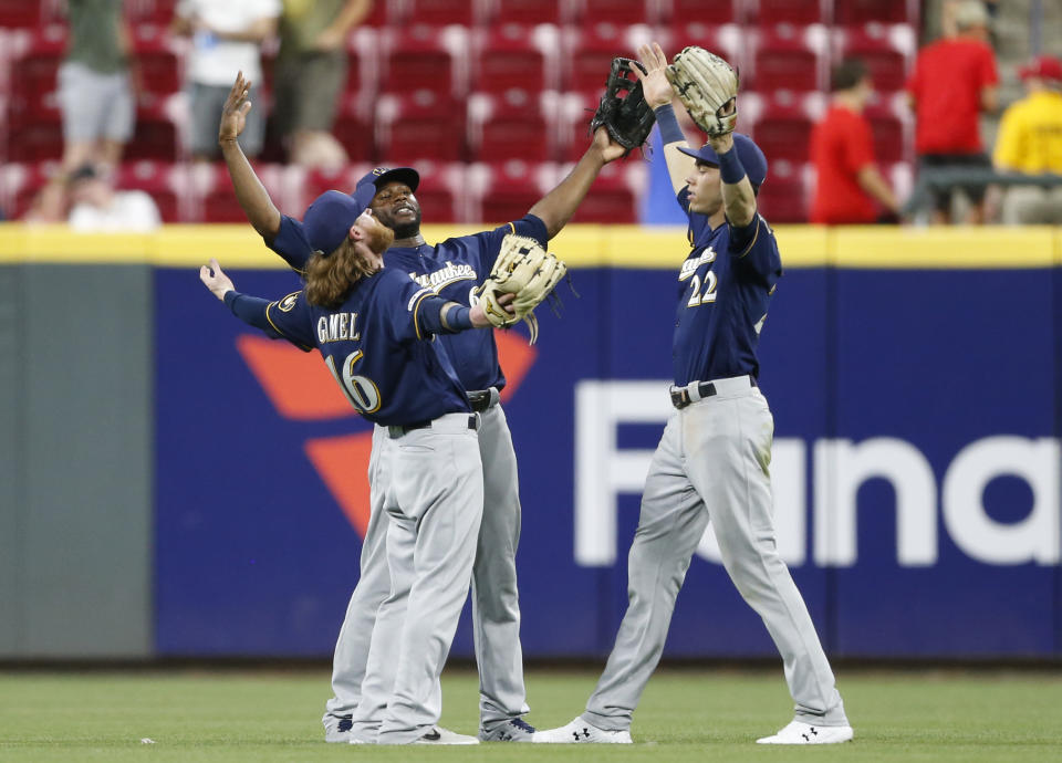 Milwaukee Brewers' Ben Gamel, left, Lorenzo Cain, center and Christian Yelich celebrates the team's 8-6 victory over the Cincinnati Reds in a baseball game, Monday, July 1, 2019, in Cincinnati. (AP Photo/Gary Landers)