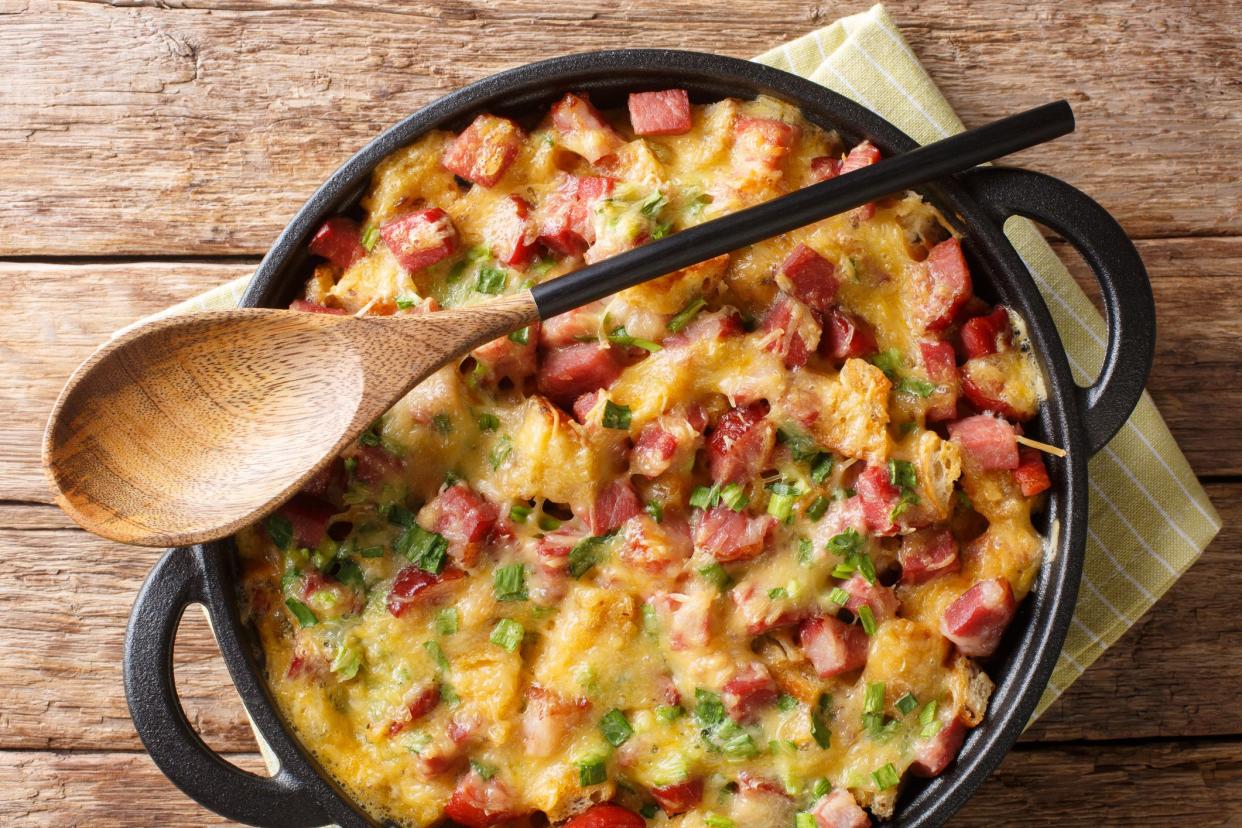 Strata bread casserole with ham, onions, cheese and eggs close-up in a pan on the table. Horizontal top view from above