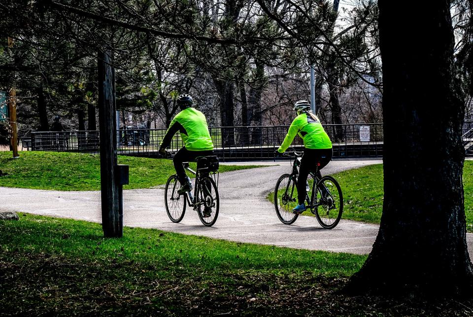 Bicyclists gets some exercise by riding on the River Trail in Lansing Sunday, April 5, 2020. 