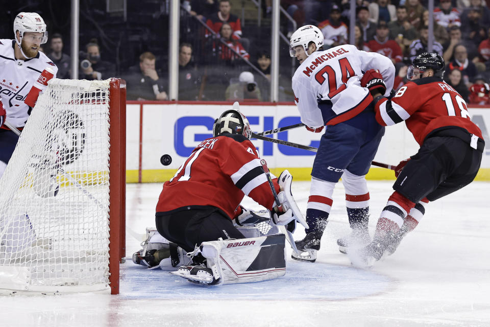 Washington Capitals center Connor McMichael (24) scores a goal past New Jersey Devils goaltender Vitek Vanecek during the third period of an NHL hockey game Wednesday, Oct. 25, 2023, in Newark, N.J. (AP Photo/Adam Hunger)