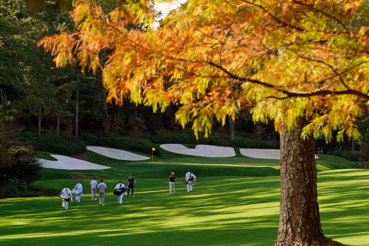 FILE - Fall leaves and November shadows highlight the 13th hole as Bubba Watson and Webb Simpson walk to the green at Augusta National on Nov. 10, 2020.